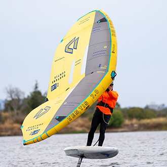 A man using a wingfoil on shoreline lake. A man using a wingfoil on shoreline lake.