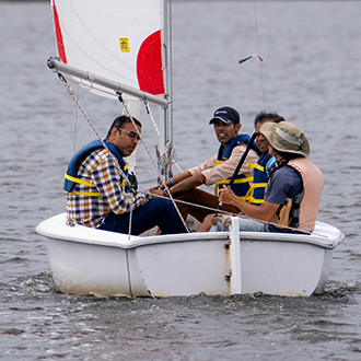 men in a sailbaot on shoreline lake receiving racing instruction men in a sailbaot on shoreline lake receiving racing instruction.