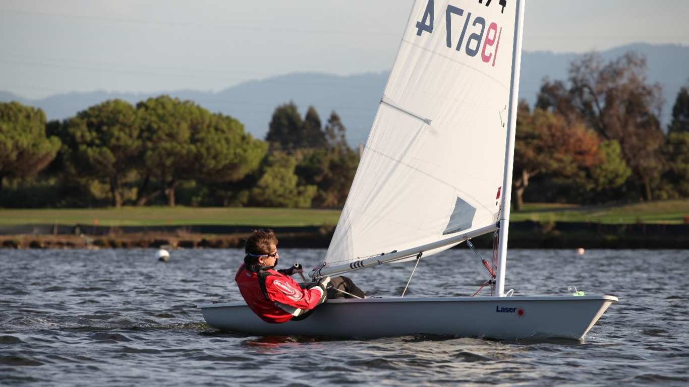 A man in a fast moving sail boat maneuvering it. A man in a fast moving sail boat maneuvering it.