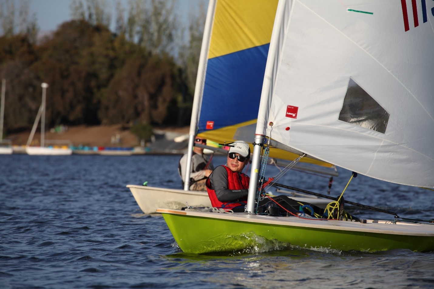 A man in a fast moving sail boat maneuvering it. A man in a fast moving sail boat maneuvering it.